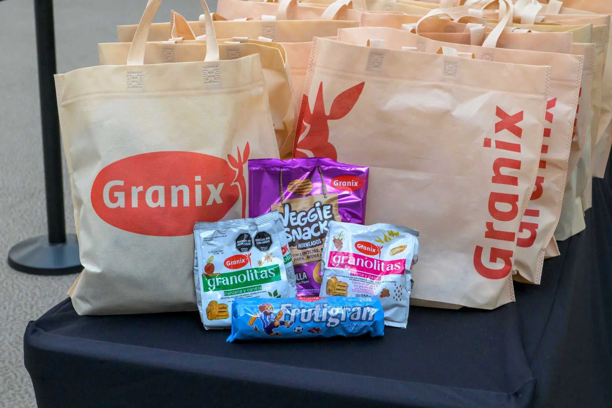 Сумки з логотипом Granix і пачки печива та снеків на столі