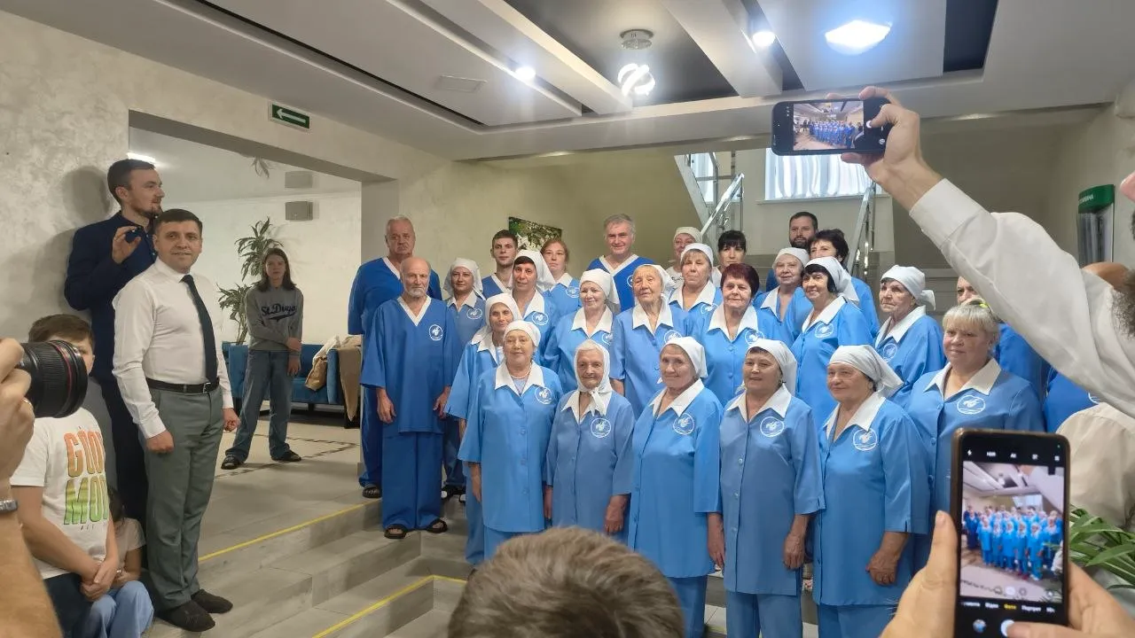 Велика група людей в однакових блакитних халатах позує для групового фото у фоє