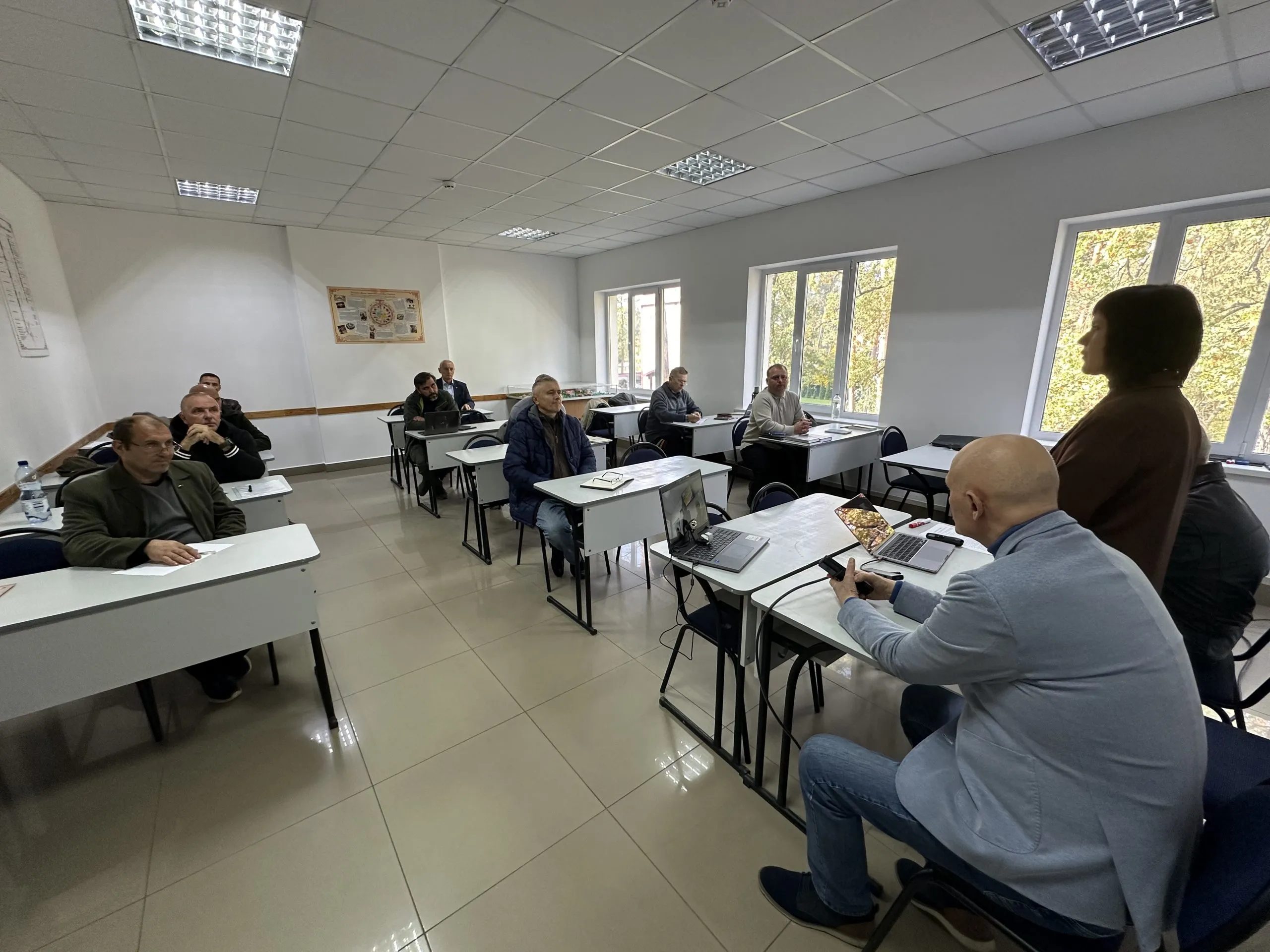 Чоловіки за партами слухають лектора в навчальній аудиторії