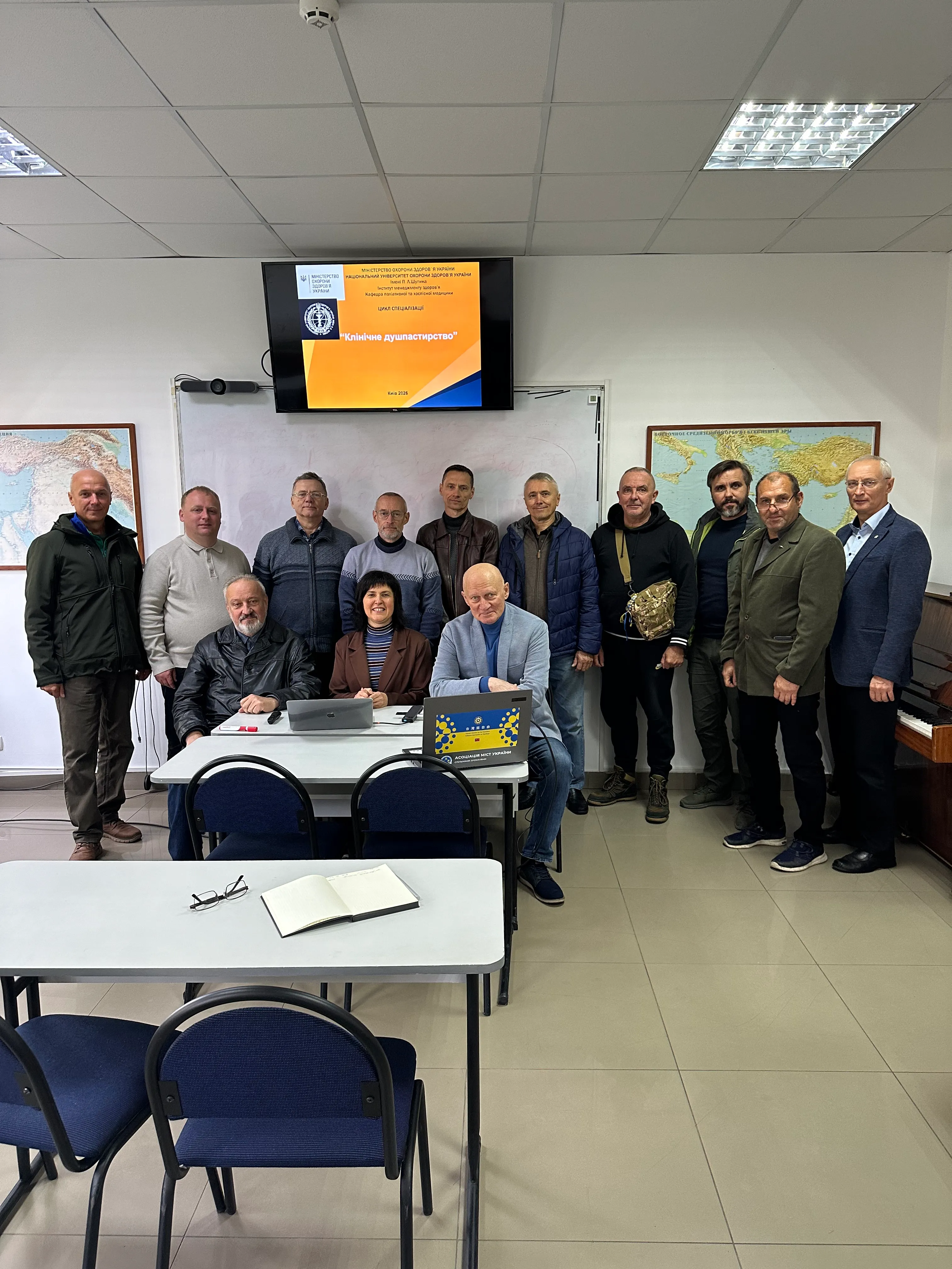 Група людей позує на фоні екрана з написом «Клінічне душпастирство» в навчальній аудиторії