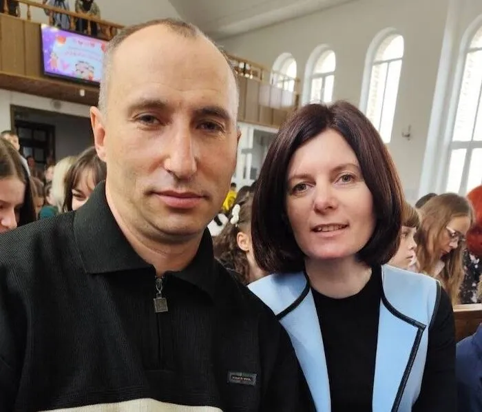 Мужчина и женщина позируют в зале церкви на фоне присутствующих людей